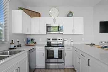 A modern kitchen with white cabinets and stainless steel appliances.